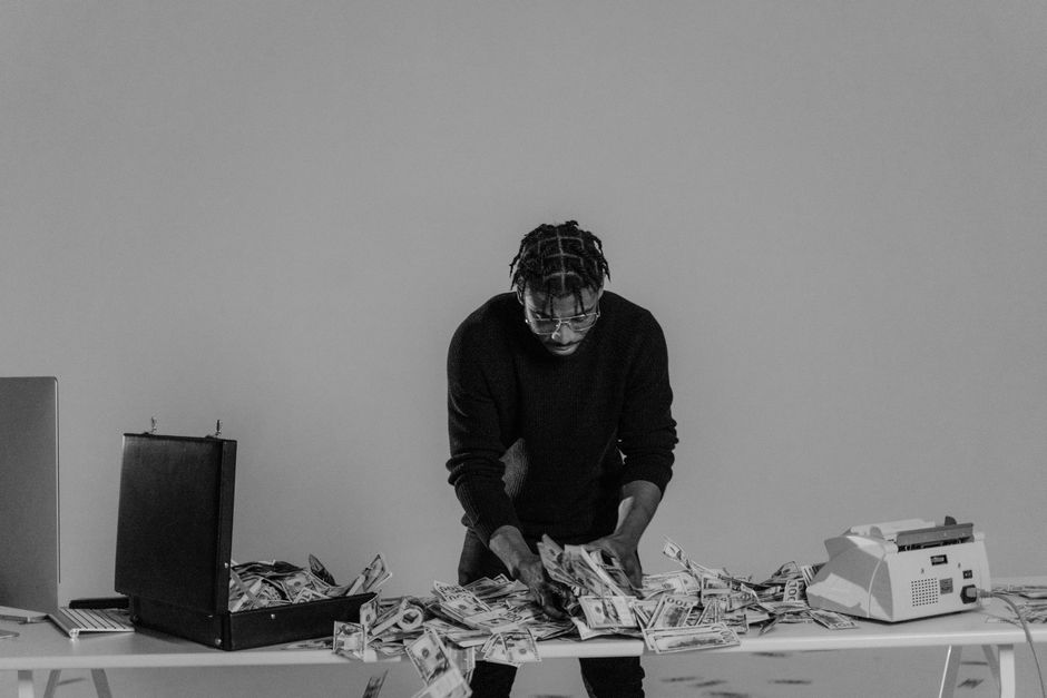 Black and white photo of a man sorting cash on a table with a briefcase.
