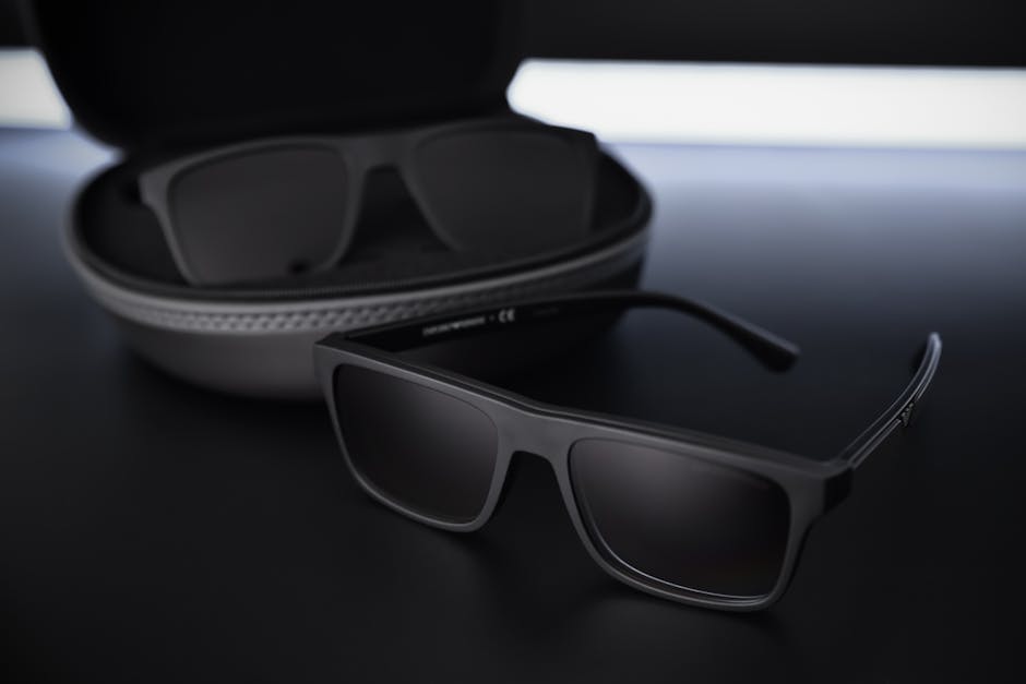 Close-up of chic black sunglasses with case on a sleek dark surface.