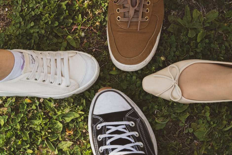 A close-up of various shoes placed together on grass, showcasing diverse styles and colors.