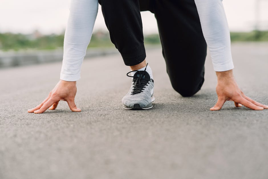 Close-up of man in starting position, ready to run on an outdoor road.