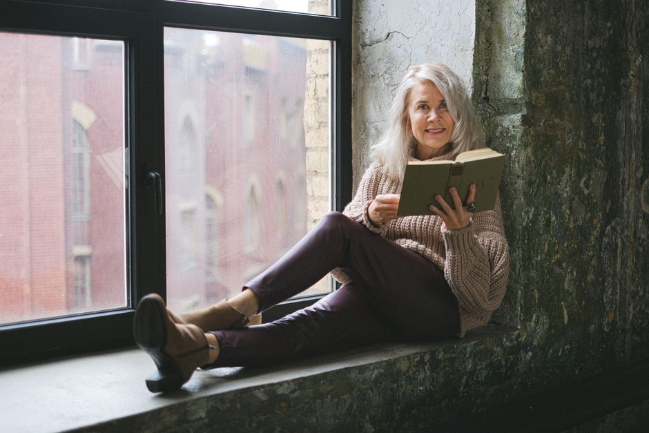 Senior woman reading by a window, bringing warmth and tranquility