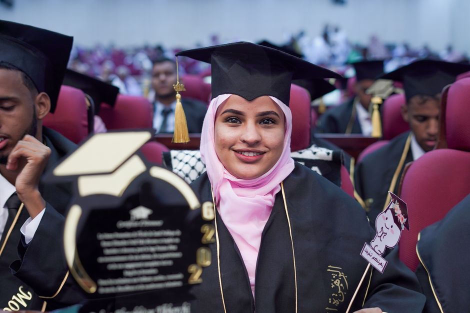 Smiling graduates in caps and gowns at a ceremony, representing academic achievement and celebration.