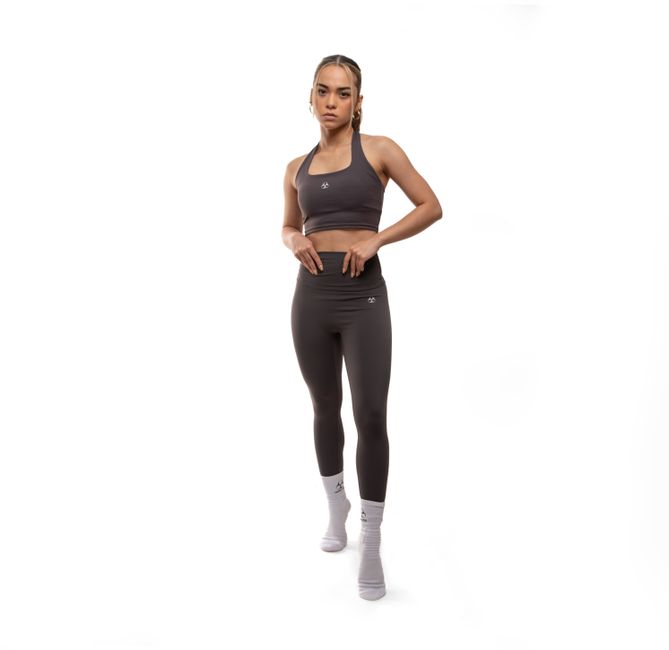Young woman wearing sports bra and leggings posing in studio on white background.