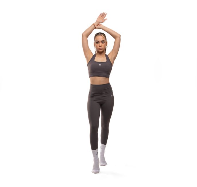 Confident woman posing in gray sportswear, emphasizing fitness and style.