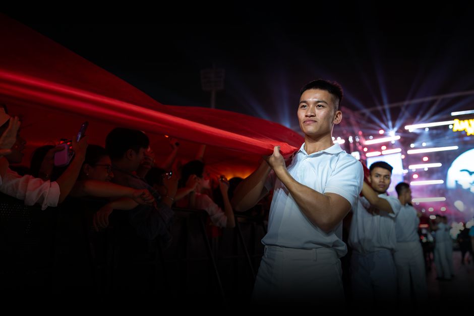 Proud young man holding a large flag at a vibrant nighttime event with lights.