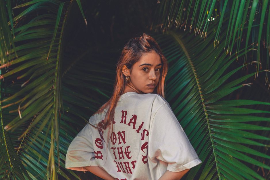 A woman stands amongst tropical leaves, creating a natural and relaxed vibe.