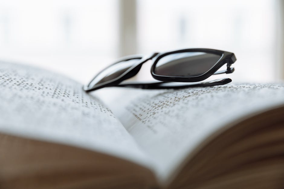 Sunglasses resting on an open Braille book, suggesting assistive technology for the visually impaired.