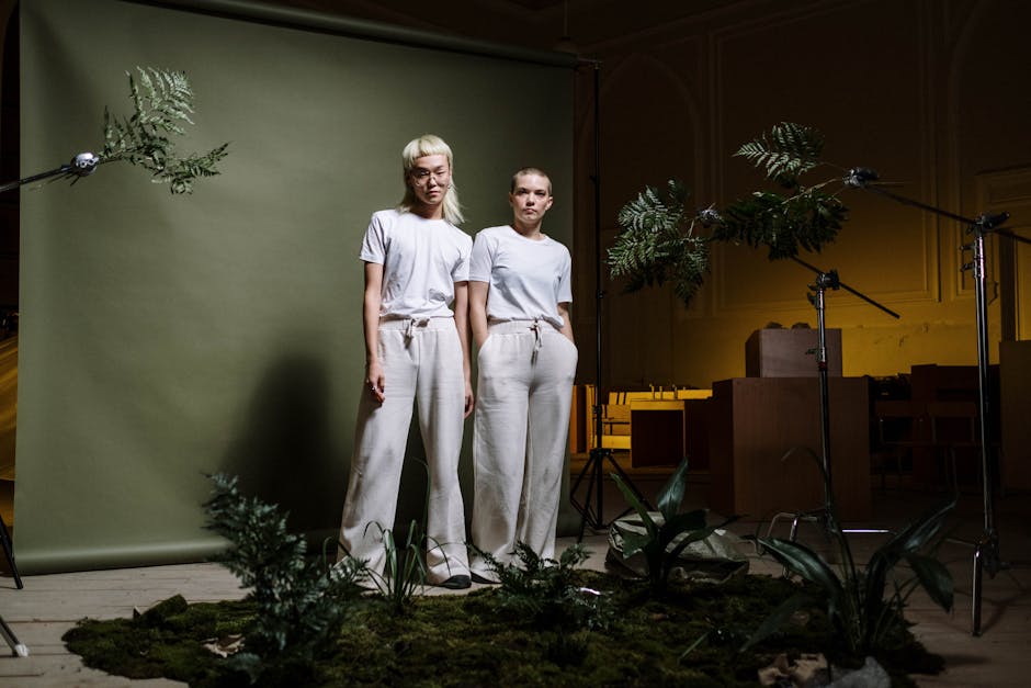 Two women standing in a nature-themed indoor studio with a green backdrop and plants.