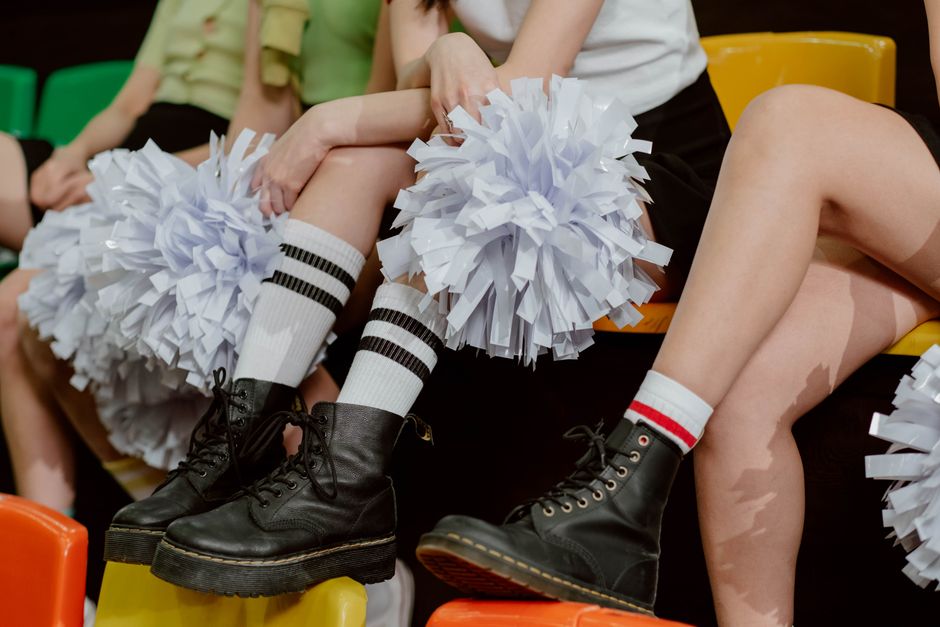 Close-up of a cheerleading squad's fashion-forward style with black boots and white pompoms.