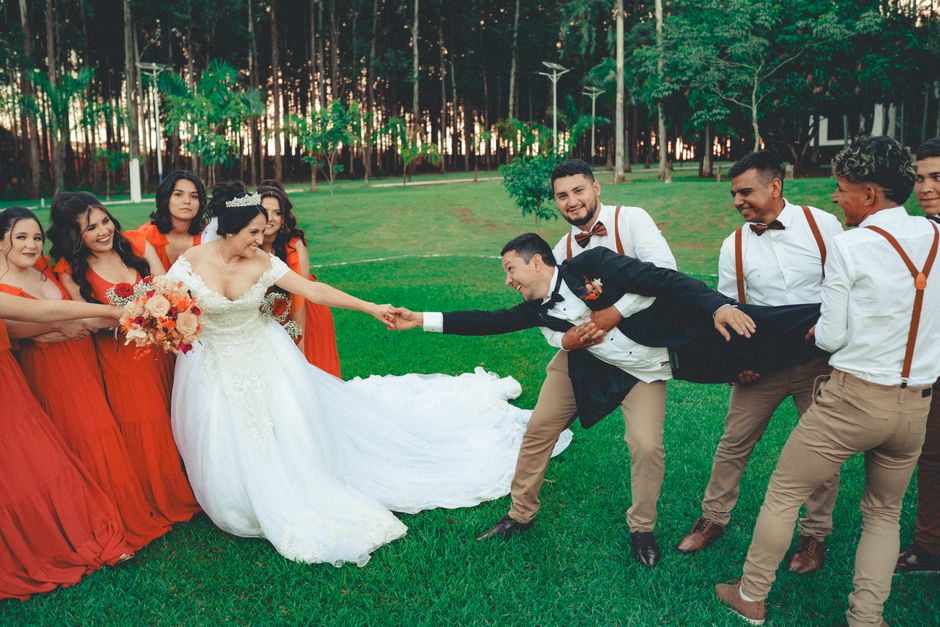 Bride, groom, and wedding party in a playful outdoor tug-of-war during the ceremony.