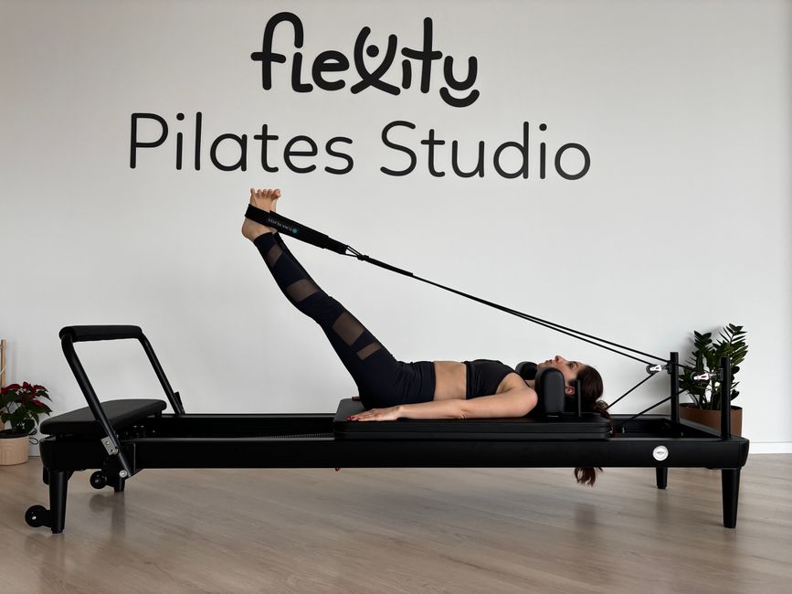 Woman performing pilates exercises on a reformer at Flexity Pilates Studio.