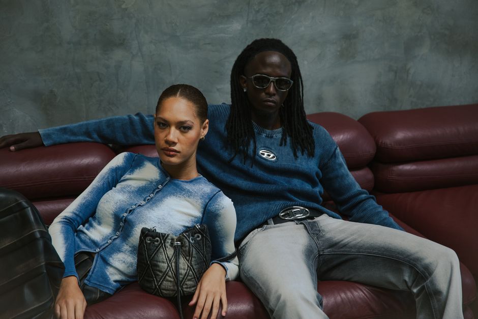 Stylish couple in trendy clothing relaxing indoors on a modern leather sofa in a chic setting.